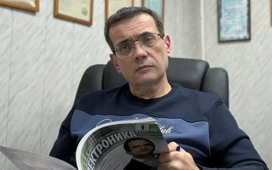 Alexander L. Litvin reading an electronics industry publication in his office